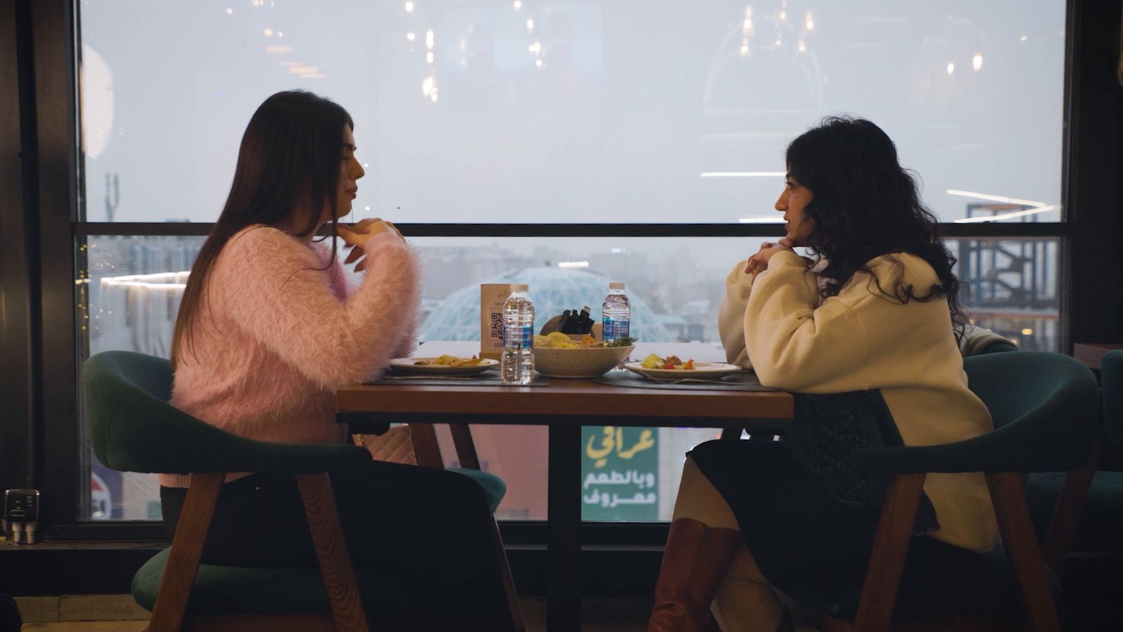 Two women sharing a meal by the window
