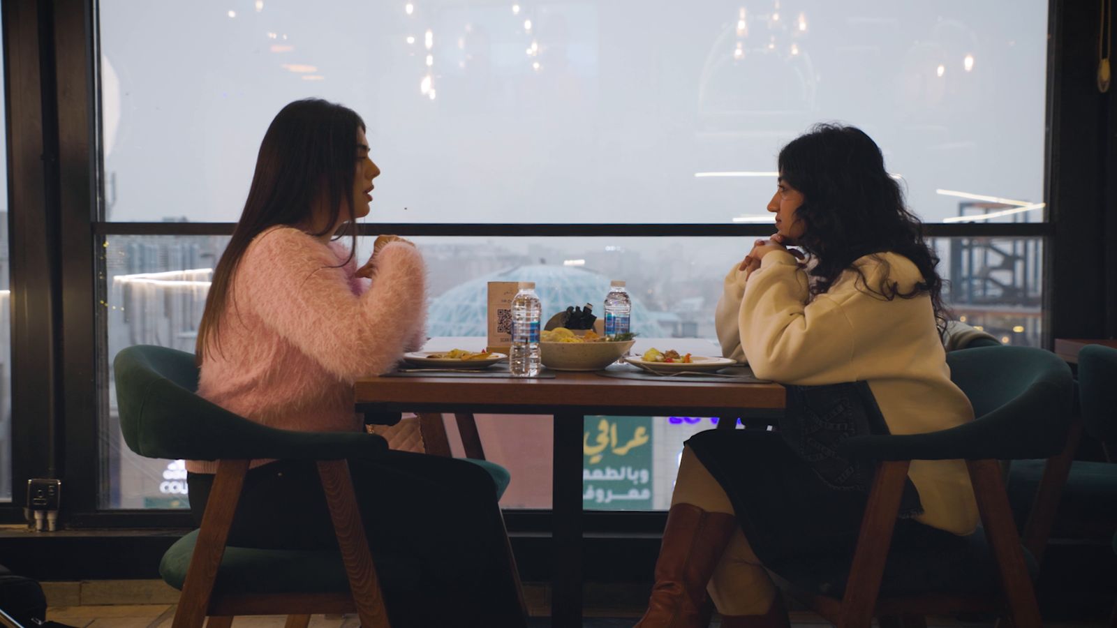 Two women talking at a window table in a restaurant