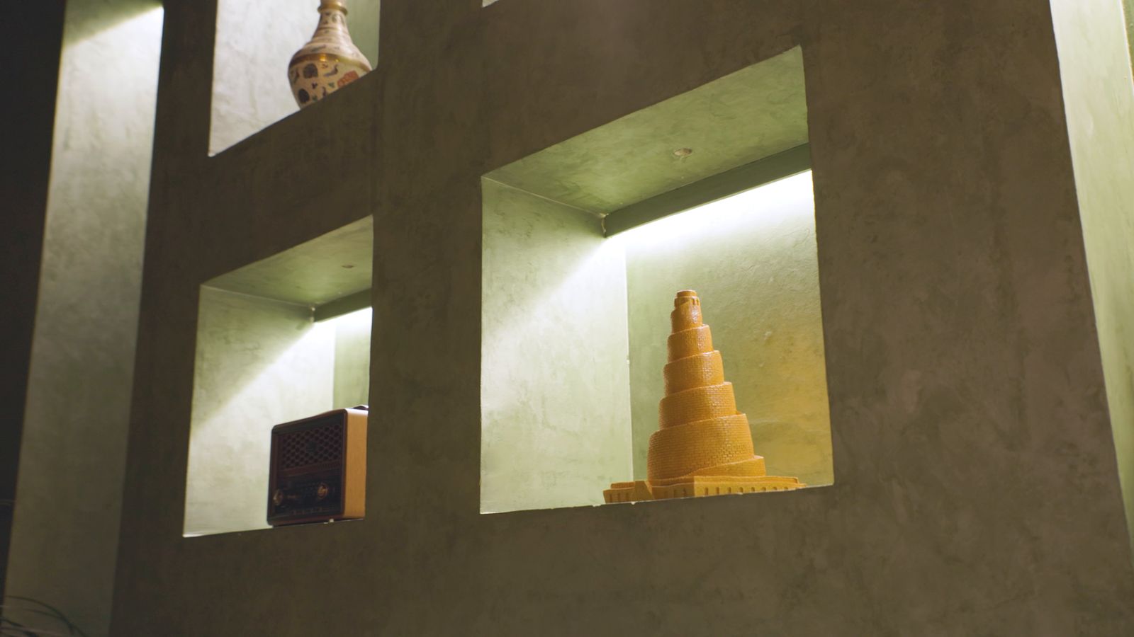 A glowing wall niche with a golden spiral tower sculpture