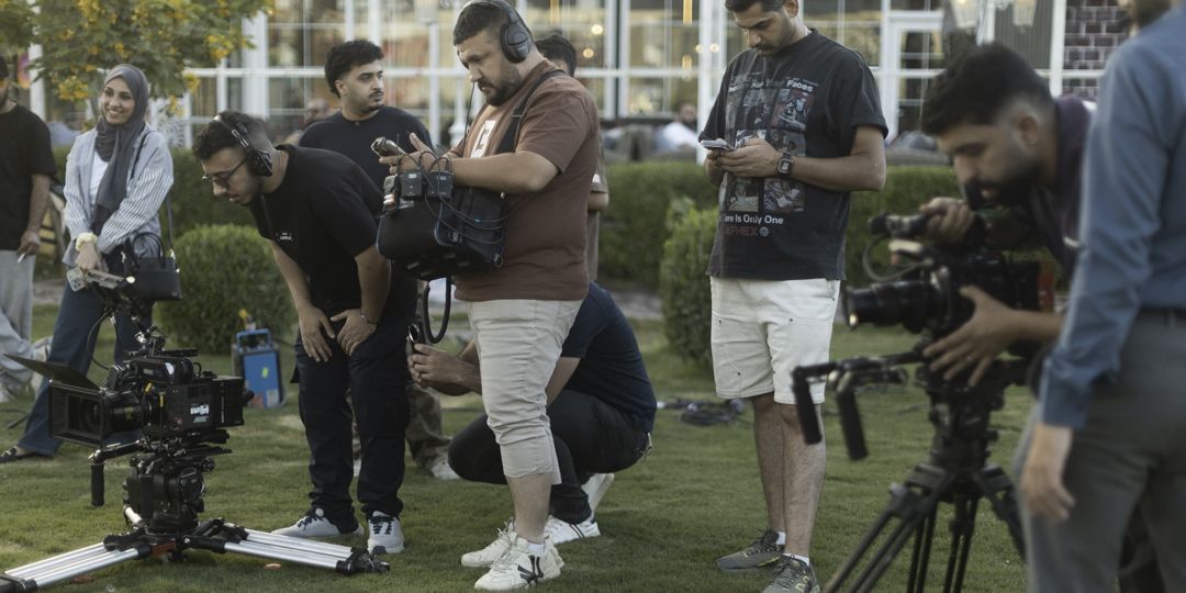 Crew with cinema cameras on a lawn, one operator filming while others check monitors