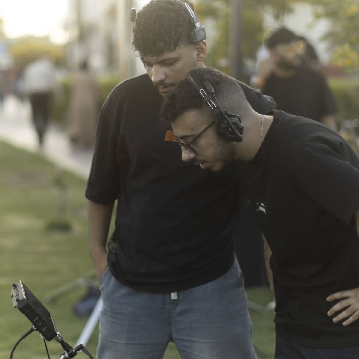 Two crew members with headsets watching a monitor on set