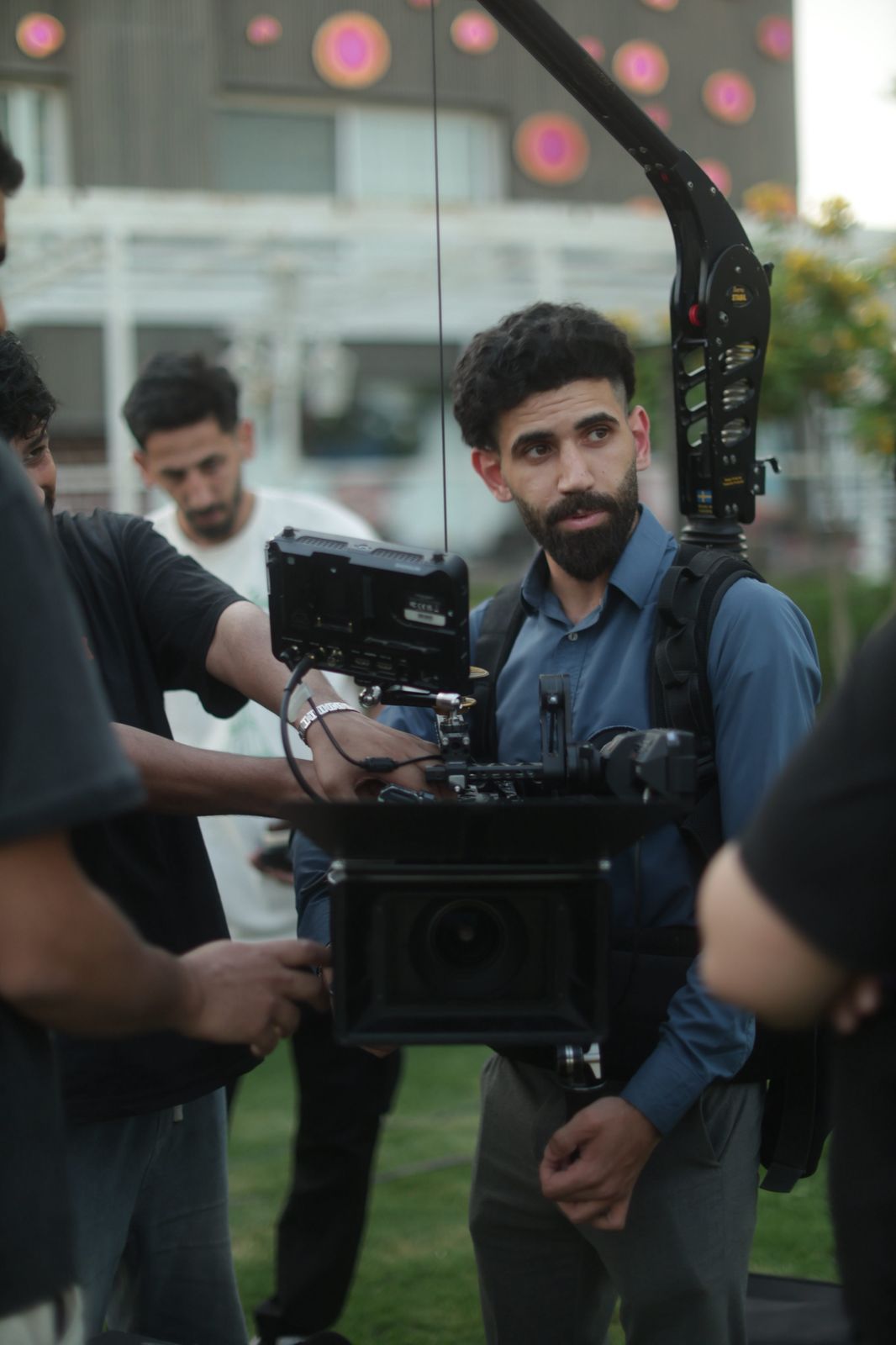 A camera operator in a stabilizing rig with a monitor on set