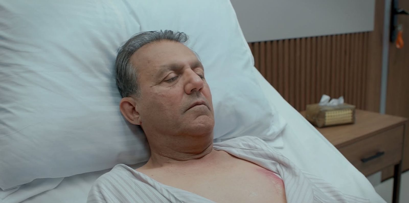 An older man resting in a hospital bed